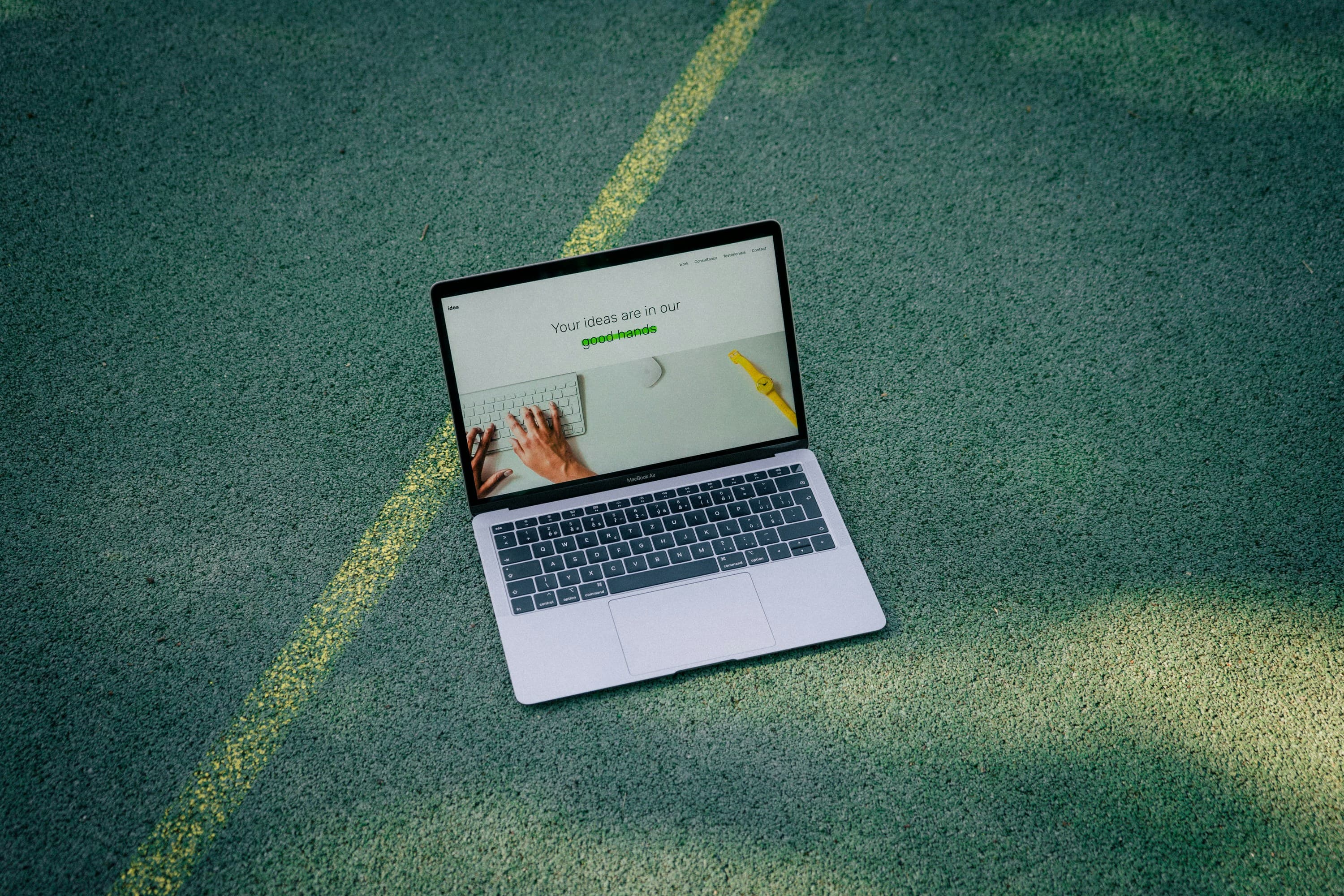 Laptop displaying a clean website on a green outdoor surface